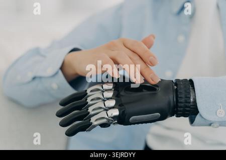 Close Up of Prosthetic Hand Being Touched by Human Hand Showing Modern Bionic Arm Detail in Soft Medical Technology Setting Stock Photo