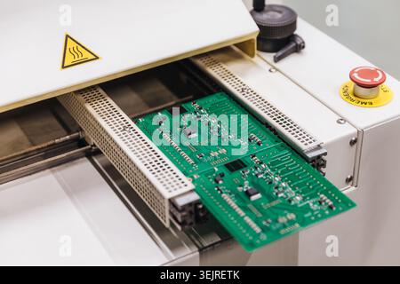 Printed circuit board moves through industrial electronics manufacturing machine Stock Photo