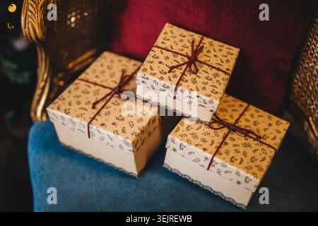 Wrapped Christmas gift boxes with red ribbons rest on vintage velvet chair Stock Photo