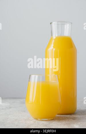 Orange juice in glass and carafe on concrete table in minimalist kitchen setting Stock Photo