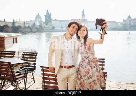 Young couple taking selfie with camera by river in Prague city center Stock Photo