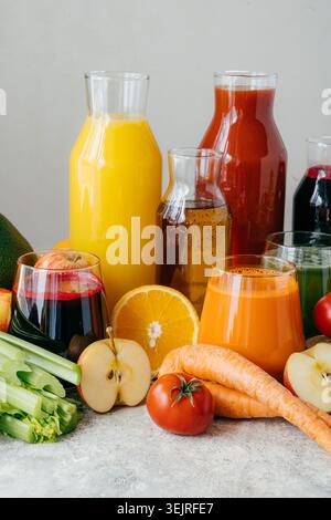 Fresh fruit and vegetable juices in glass bottles with apples carrots celery tomato and orange Stock Photo