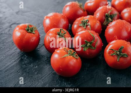 Fresh cherry tomatoes with water drops on dark stone kitchen surface Stock Photo