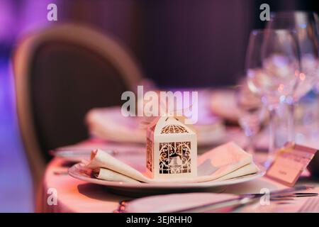 Wedding reception table setting with favor box, folded napkin, and wine glasses Stock Photo