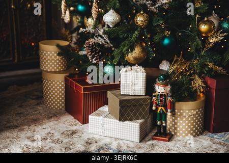 Christmas gifts and nutcracker stand under decorated tree with ornaments and lights Stock Photo