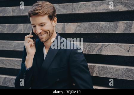 Businessman talking on smartphone while sitting on stone steps outdoors Stock Photo