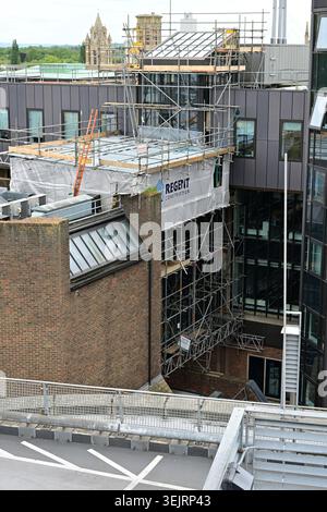 Cambridge, UK - May 17, 2026: Construction scaffolding on modern building beside historic urban city skyline Stock Photo