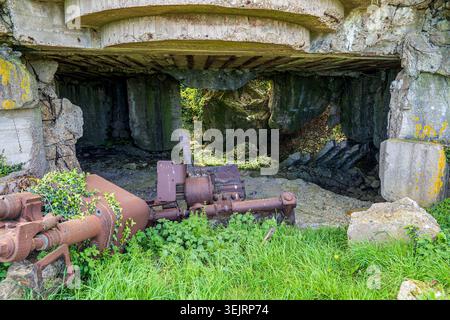 Close-up shot of the gutted interior of a concrete bunker in Longues-sur-Mer. Collapsed heavy concrete blocks, a ceiling with metal beams, and rusted Stock Photo