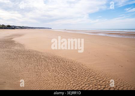 A close perspective shows the geometric ripples shaped by water on the golden sand of Omaha Beach, Normandy. The deserted coastline stretches as far a Stock Photo