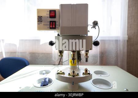 An industrial automatic button and rivet setting machine with red rocker switches on the electrical control panel is positioned on a worktable surface Stock Photo