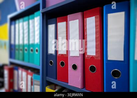 Row of various lever arch folders and office ring binders arranged on blue storage shelves in an office or archive environment for systematic document Stock Photo