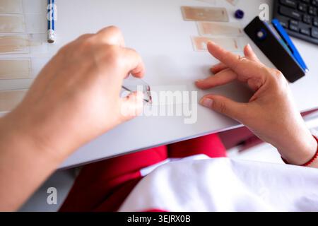 High-angle close-up view of a laboratory technician using glass microscope slides to prepare a peripheral blood smear specimen for analysis on a desk Stock Photo
