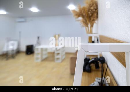 A close-up shot of a white metal furniture frame mounted on a wooden wall panel inside a modern brightly lit room with a blurry background containing Stock Photo