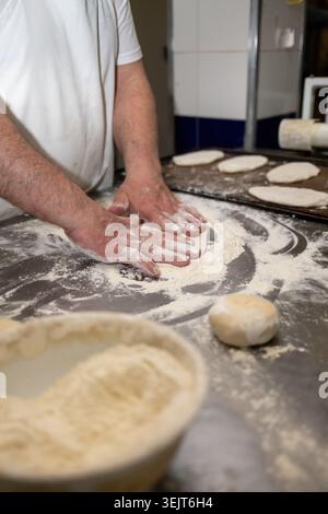 Baker hands kneading dough with flour on counter Stock Photo