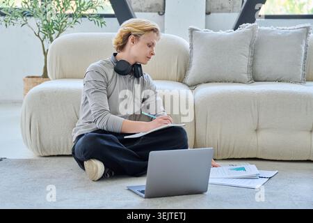 Young student studying with laptop on floor at home Stock Photo