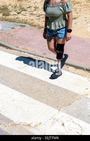 Woman with prosthetic leg walking on crosswalk Stock Photo