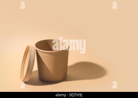 Empty craft paper soup cup with shadow on brown paper background. Ecological individual package. Zero Waste. Mock up. Stock Photo