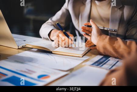 The businesswoman is using a white calculator to check company financial information, she is checking company financial information from the documents Stock Photo