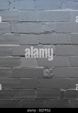 Black painted concrete cinder block and mortar wall surface with smooth and rough blocks, broken brick pieces, thick uneven mortar joints Stock Photo
