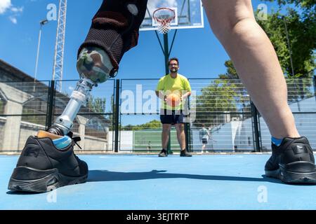 Amputee man playing basketball with prosthetic leg Stock Photo