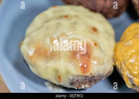 cooking Hamburg steak. One captures a patty sizzling in its juices, and the other features a patty with perfectly melted cheese. Stock Photo