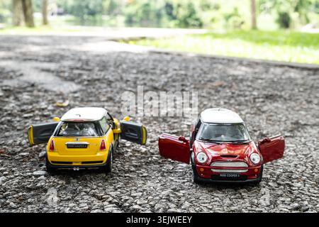 Chiang Mai, Thailand - 25 May 2026 : Two Mini Cooper S red and yellow diecast toy cars on asphalt road red in focus front view open doors Stock Photo