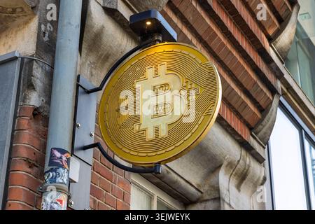 Amsterdam, Netherlands, May 23, 2026. A round golden physical Bitcoin cryptocurrency symbol sign mounted on a brick building exterior wall in the city Stock Photo