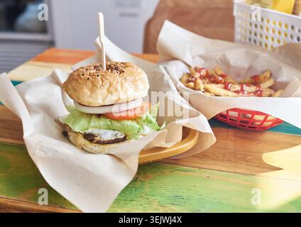 A handmade burger stacked with fresh ingredients and a side of seasoned golden fries are beautifully captured, highlighting authentic comfort food. Stock Photo