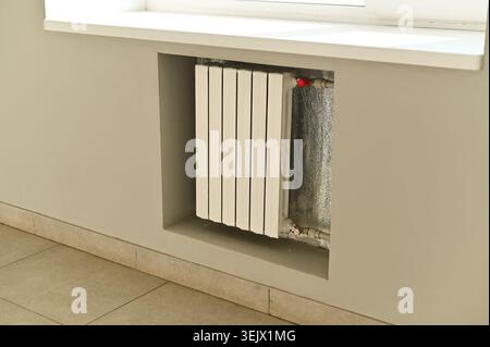 Indoor radiator under window with vertical white panels, heating system in clean interior space, radiator offering warmth and comfort, modern building Stock Photo