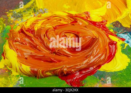 Orange oil paint roughly mixed on colorful palette from cadmium red and yellow Stock Photo