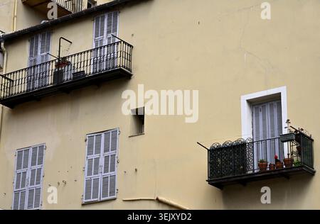 Balconies and windows closed with shutters on plane wall of building Stock Photo