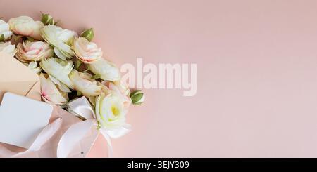 Festive composition featuring a quilted pink gift bag filled with cream and blush artificial rose flowers, accented by a white ribbon bow and gift car Stock Photo