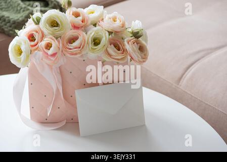 Delicate lifestyle composition featuring a quilted pink gift bag filled with cream and blush ranunculus flowers, accented by ribbon handles and decora Stock Photo