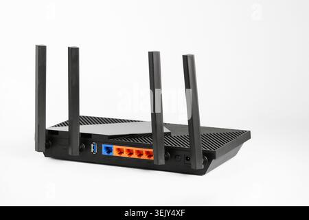 Black wireless router with four antennas and multiple LAN ports isolated on white background. Concept of home internet, networking, broadband connecti Stock Photo