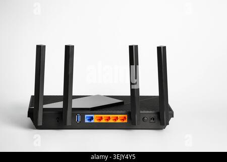 Black wireless router with four antennas and multiple LAN ports isolated on white background. Concept of home internet, networking, broadband connecti Stock Photo