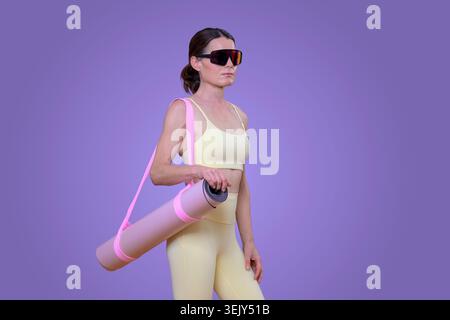 sporty woman carrying a yoga exercise mat, purple background Stock Photo
