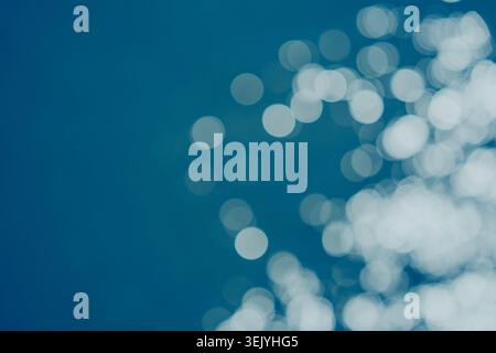 Abstract sunlight reflections create soft bokeh circles across blue ocean water. Stock Photo