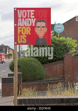 Tall signs, Andy Burnham Labour poster and Reform UK signs face voters on Ashton-in-Makerfield street before the Makerfield by-election. Stock Photo