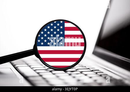 United States flag displayed on laptop screen through magnifying glass. Technology background illustrating digital business cybersecurity and online s Stock Photo