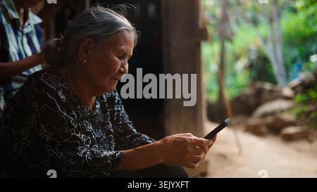 Elderly asian woman using smartphone, connecting to global technology Stock Photo