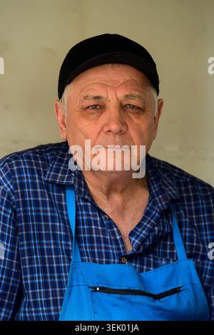 Tashkent, Uzbekistan - April 8 2026: Uzbek Man Wearing an Apron and a Cap at the Chorsu Bazaar Stock Photo