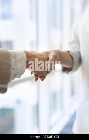 Close up of two women shaking hands in office Stock Photo