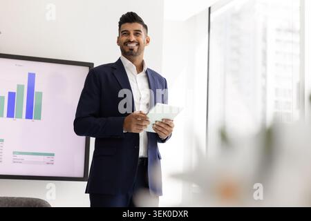 Confident businessman holding digital tablet stands in modern office Stock Photo