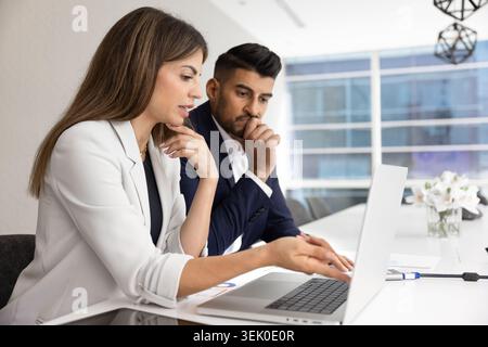 Indian and Hispanic teammates reviewing data on laptop Stock Photo