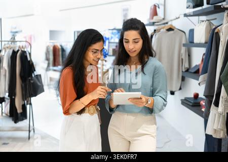 Coworkers working together in boutique store, reviewing data on tablet Stock Photo