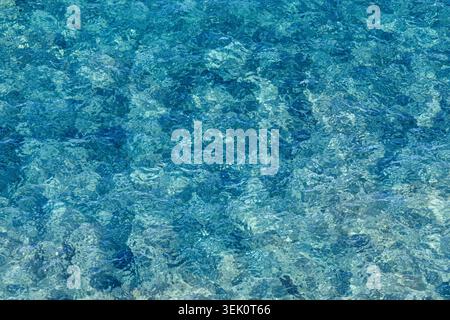 High-angle view of glistening turquoise sea water with bright sun glare and ripples on the surface. Captured on the coast of Italy, this vibrant liqui Stock Photo