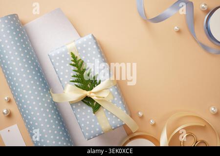 Gift box wrapped in light blue polka dot paper with cream satin bow and green fir sprig. Space for text Stock Photo