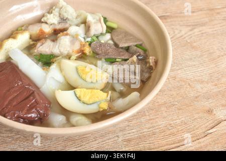 large rice noodles chop and crispy pork couple organ topping egg in clear blood soup on bowl Stock Photo