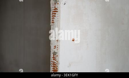 Damaged brick wall with exposed red bricks and crumbling plaster Stock Photo