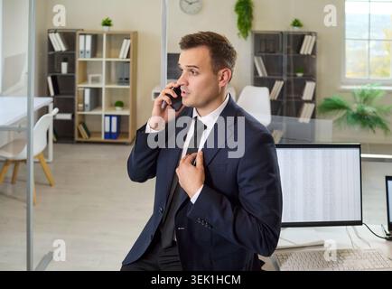 Businessman analyst on smartphone call working at computer desk in modern office Stock Photo